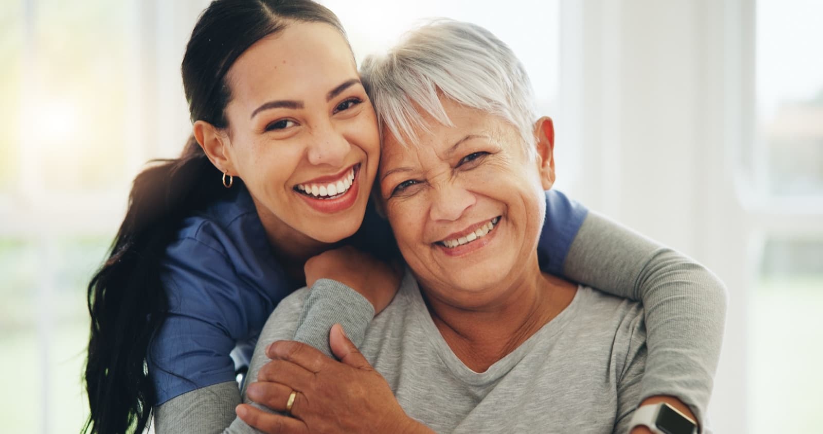 Caregiver and client smiling together in a bright, sunlit home