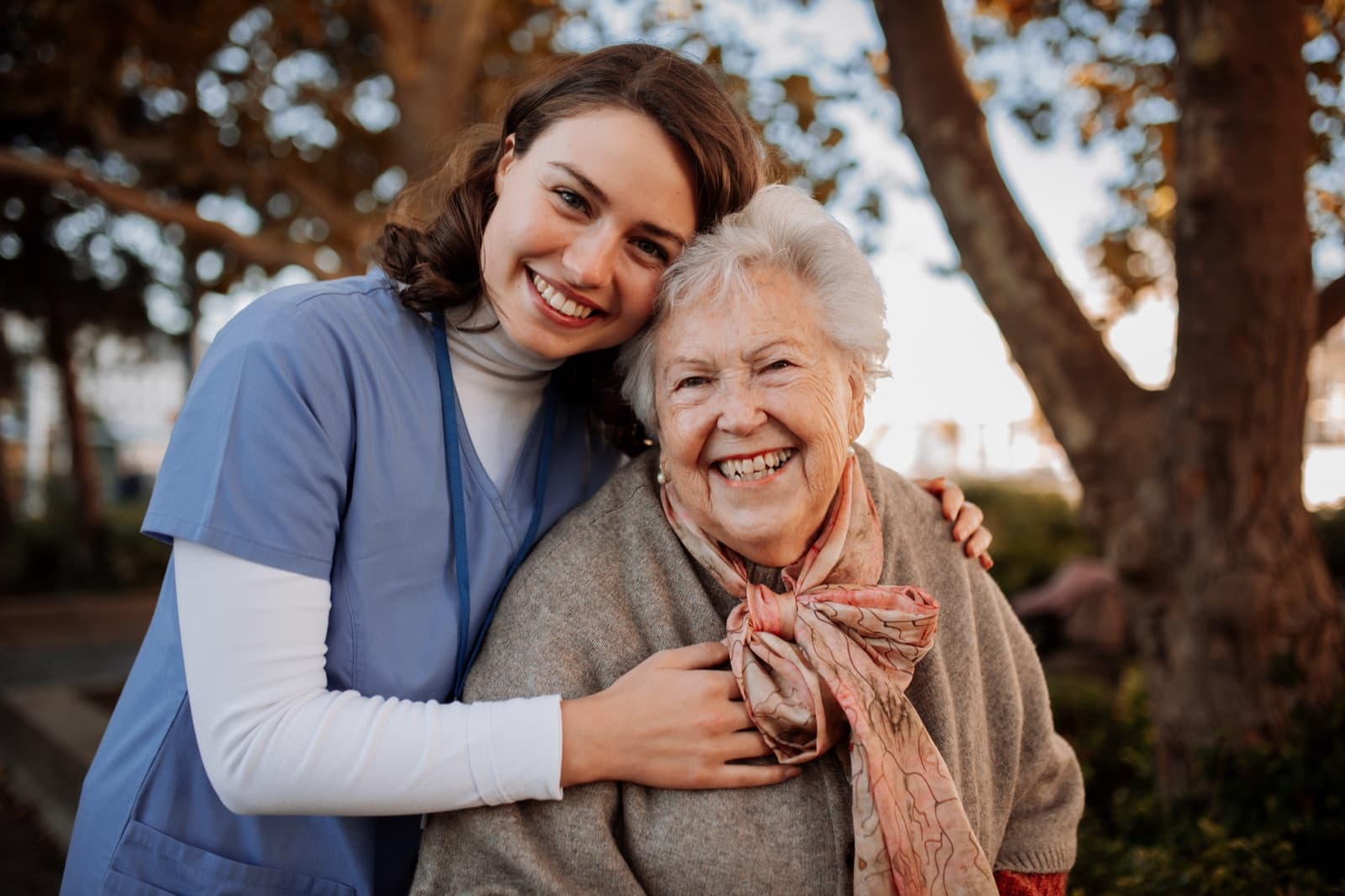 Caregiver smiling with an older adult on a sunny outdoor walk