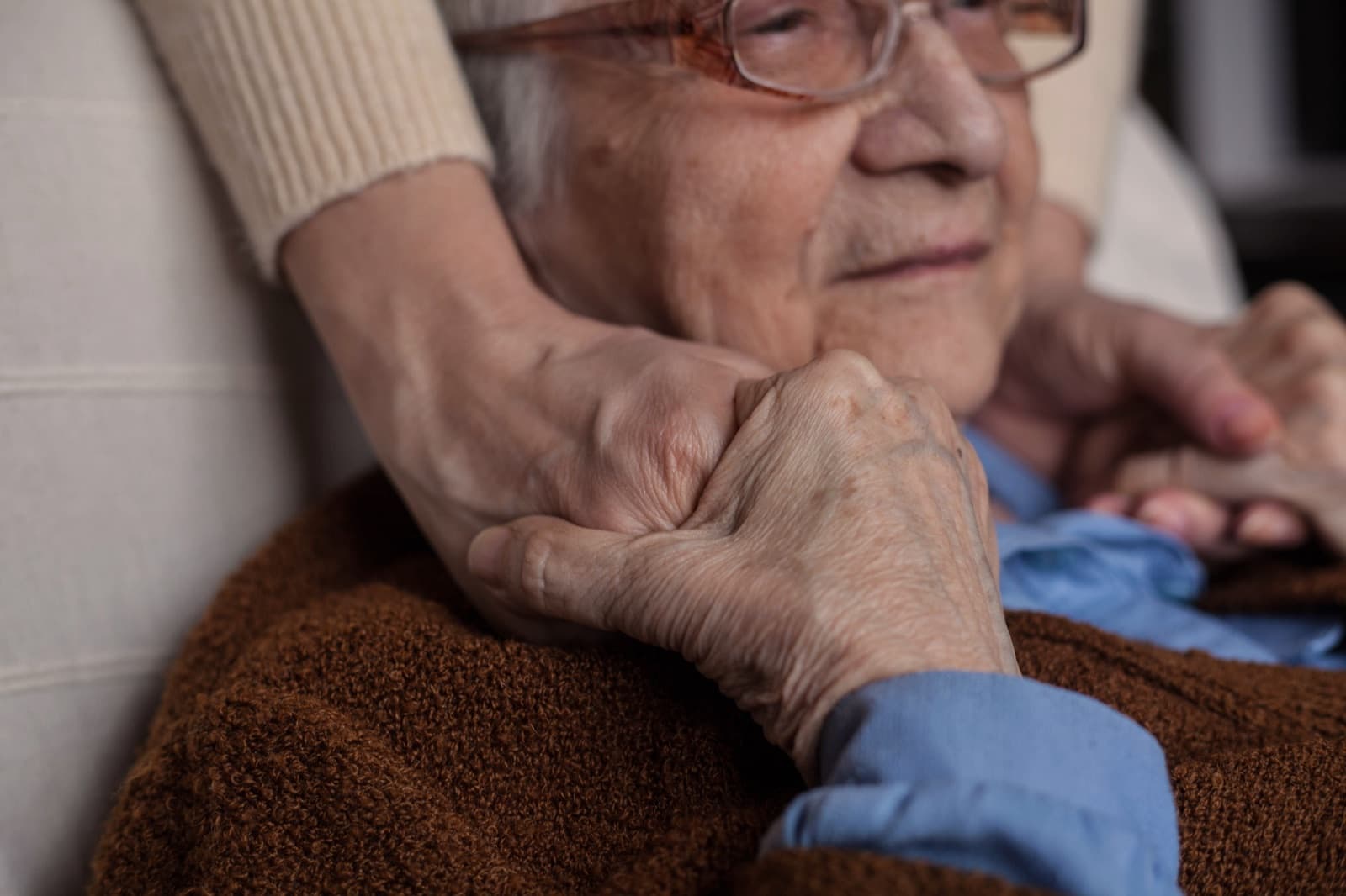 Caregiver gently holding the hands of an older adult